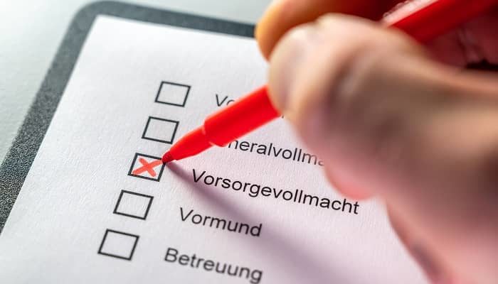 Eine Person kreuzt auf einer Liste von Wörtern, das Wort Vorsorgevollmacht an