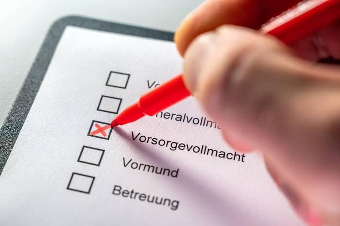 Eine Person kreuzt auf einer Liste von Wörtern, das Wort Vorsorgevollmacht an