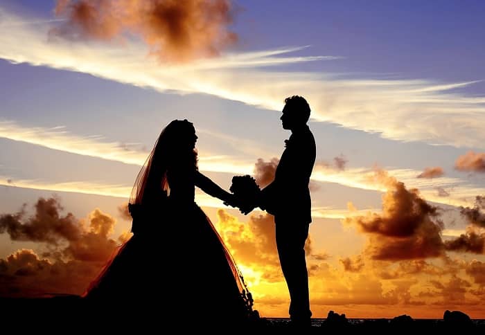 Ein Hochzeitspaar steht in freier Natur vor einem Abendrot Himmel