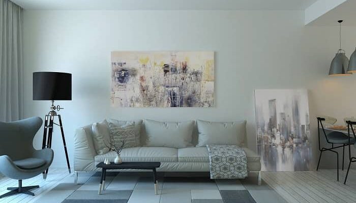 Ein großer in grau gehaltener Wohnraum mit modernen Akustikbildern über einem Sofa