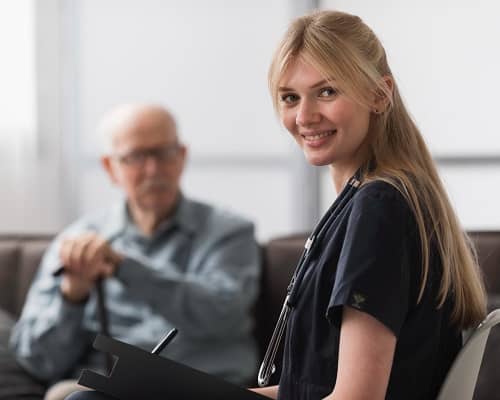 Eine Ärztin sitzt vor einem Patienten mit einem umgehängten Stethoskop 