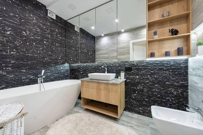 Badezimmer mit einem Badlüfter, frei stehender Badewanne und schwarz/weißen Wänden 
