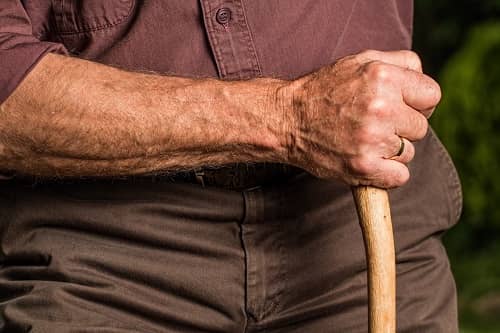 Ein Mann hält beim Wandern einen Holzstock in seiner Hand