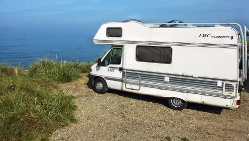 Ein Campingmobil steht auf einer Klippe mit weiter Sicht über das Meer