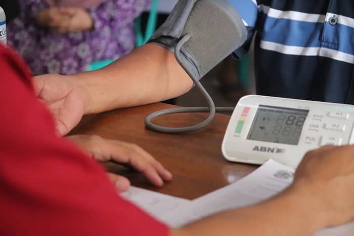 Eine Person misst bei einer anderen Person, mit Hilfe eines Blutdruck Messgerätes, den Blutdruck