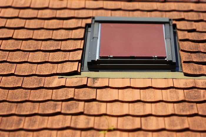 Ein Hausdach mit roten Dachziegeln und einem Dachfenster