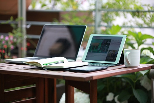 Ein schöner Schreitisch mit einem Laptop, einem Bildschirm, Notizbuch und Blick nach draußen