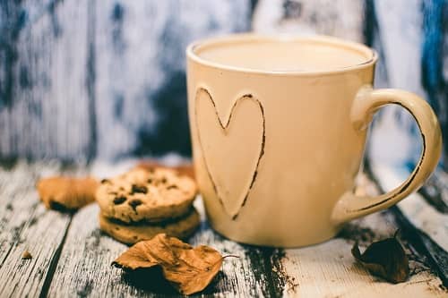 Eine Tasse mit Kaffee, daneben ein Keks, stehen auf einem Tisch