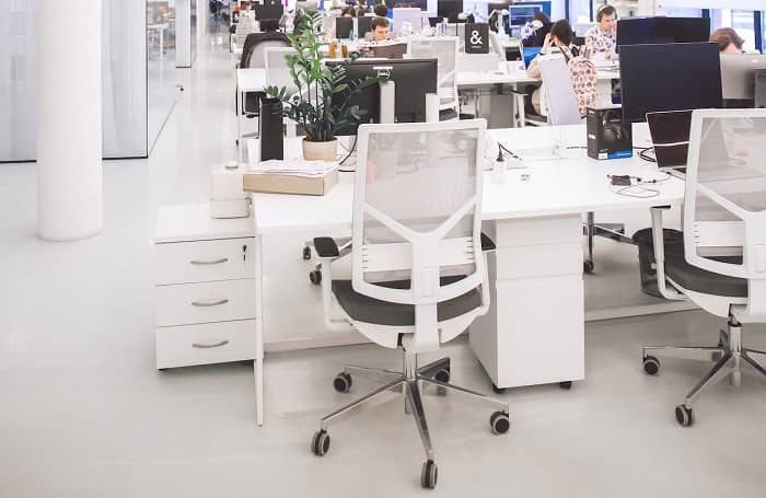 Ein weißer Schreibtisch mit einem Bürodrehstuhl davor