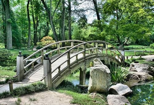 Eine Holzbrücke führt über einen Bachlauf mit großen Steinen