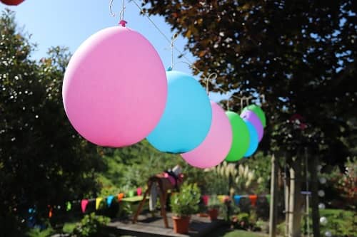 Bunte Luftballons hängen in einem Garten, der für eine Party vorbereitet ist.