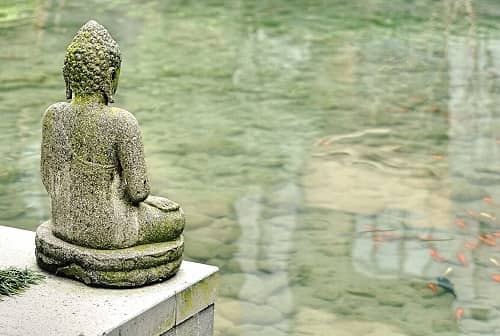 Eine große Buddha Statue steh am Rande eines Teichs