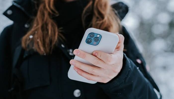 Eine Frau steht im Freien und hält Ihr Handy in der Hand