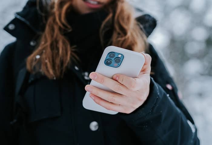 Eine Frau steht im Freien und hält Ihr Handy in der Hand