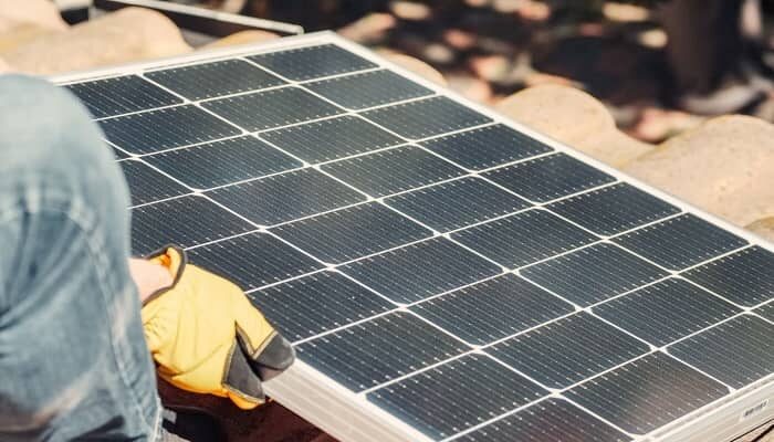 Ein Mann montierzt auf einem Dach ein Solarpanel