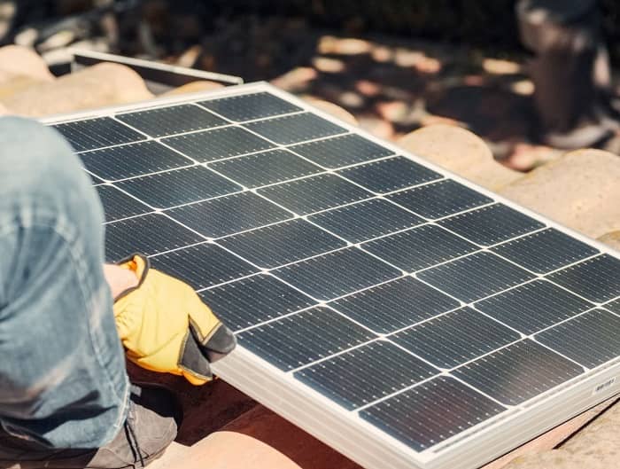 Ein Mann montierzt auf einem Dach ein Solarpanel