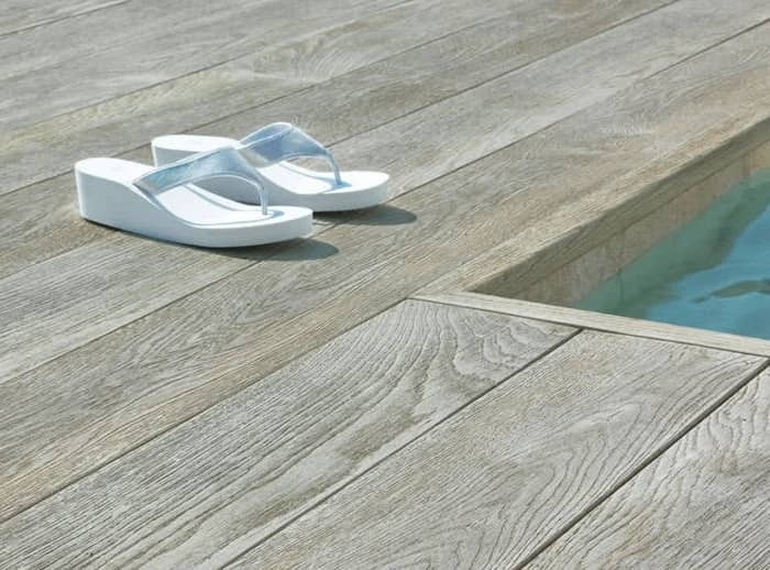 Ein Holzoptik Terrassenbelag, auf dem Badeschuhe stehen