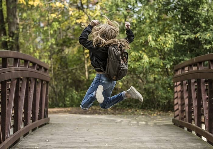 Ein Mädchen springt auf einer Brücke vor Freude in die Luft
