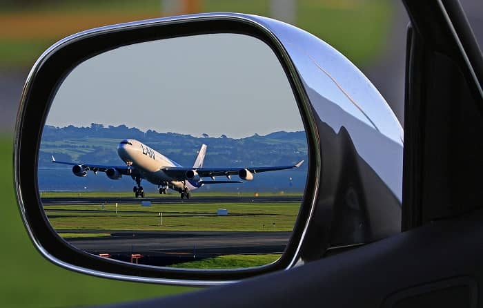 In einem Autoseitenspiegel sieht man ein Flugzeug starten