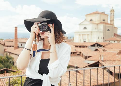 Eine Frau mit Fotoapparat steht auf einer Terrasse und macht Bilder 