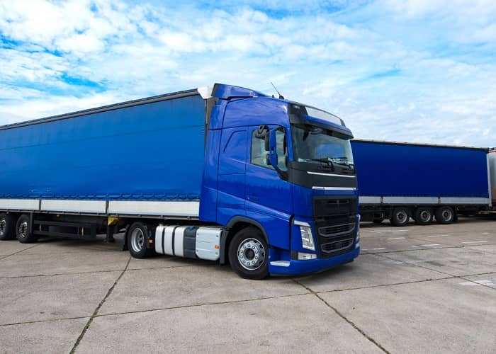 Ein großer blauer LKW mit Auflieger in einem Hof