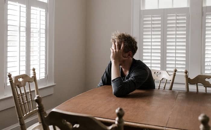 Ein Mann sitzt traurig und niedergeschlagen an einem Tisch