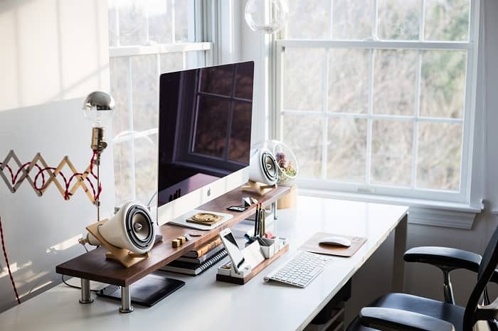 Ein Schreibtisch mit Bildschirm und Tastatur am fenster