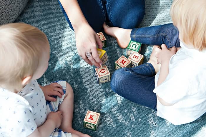 Eine Frau spielt mit zwei Kindern am Boden