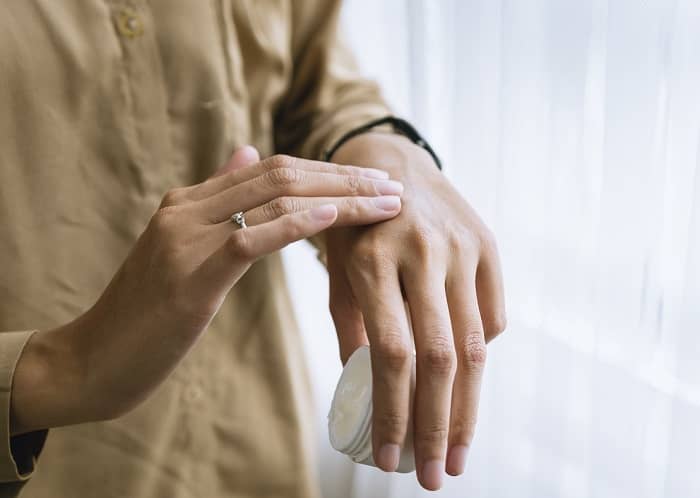 Eine Frau schmiert sich mit Creme die Hand ein