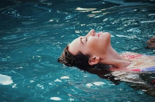 Eine Frau schwimmt in einem Pool auf dem Rücken
