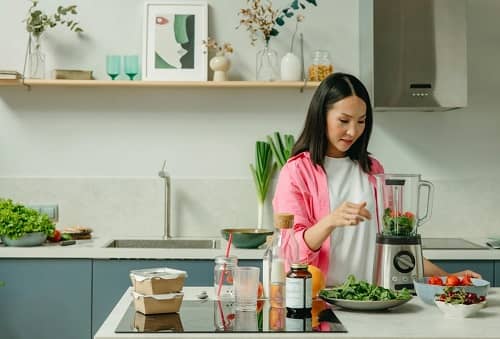 Eine Frau steht in der Küche und macht sich einen Smoothie