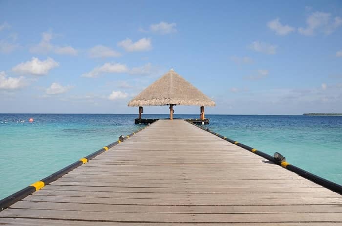 Ein langer Steg ins Meer, an dessen Ende eine offene Strohhütte steht