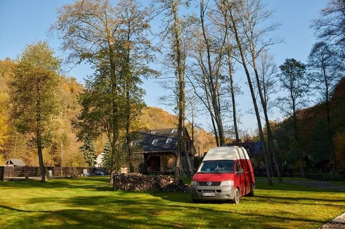 Ein Campervan steht in freier Natur unter Bäumen
