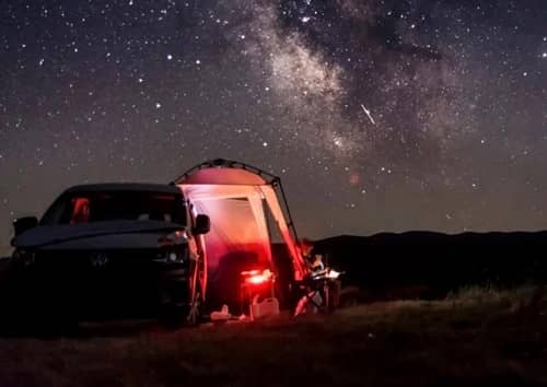 Ein Camper steht nachts vor einem wunderbaren Sternenhimmel