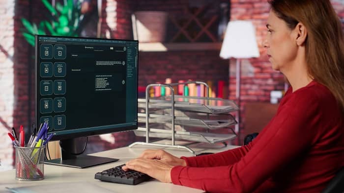 Eine Frau sitzt vor dem Bildschirm und schreibt auf der Tastatur