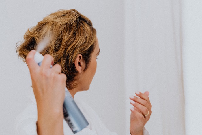 Eine Frau sprüht sich die Haare ein